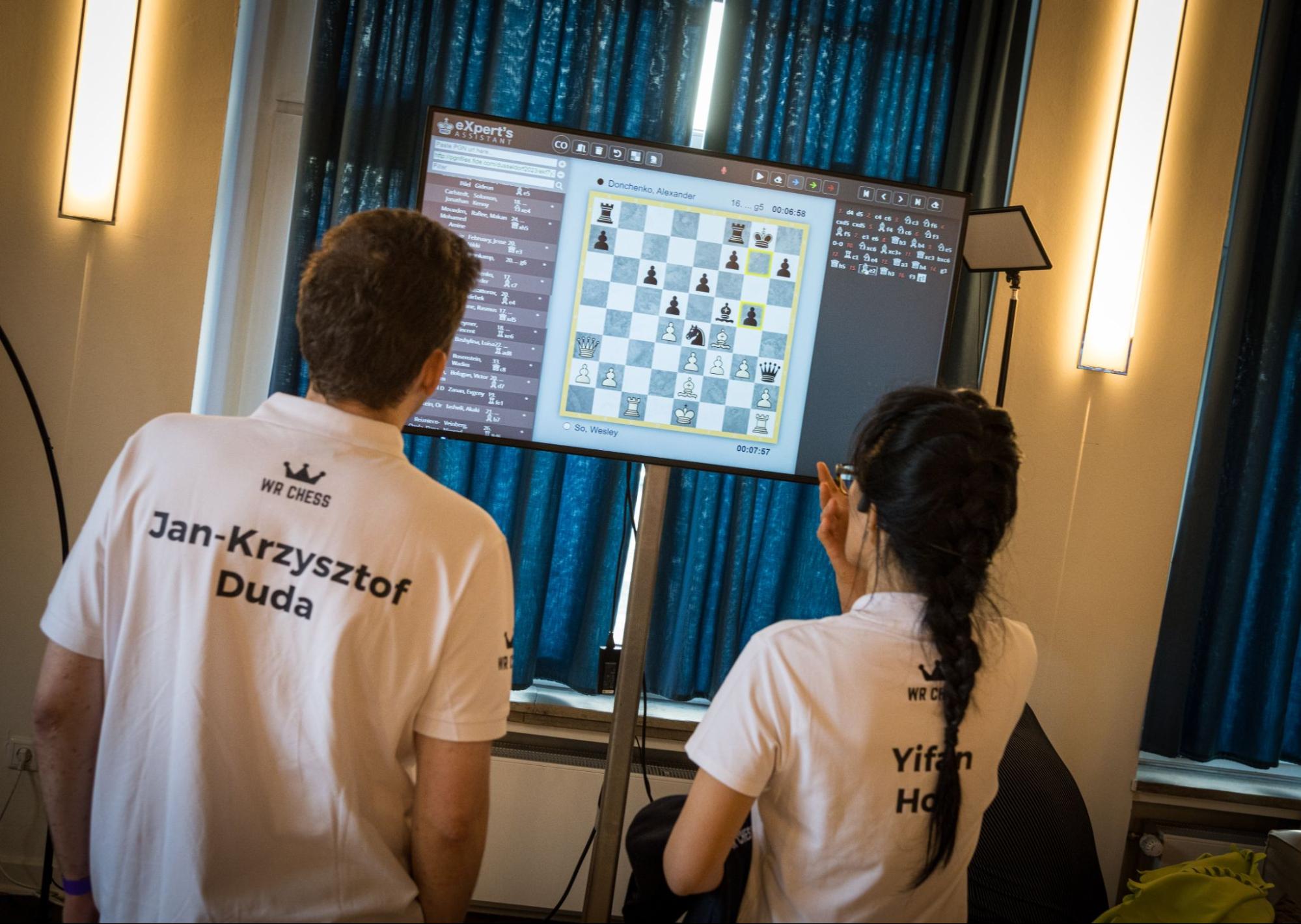 Jan-Krzysztof Duda and Hou Yifan follow the wild duel between Wesley So and Alexander Donchenko. | Photo: Lennart Ootes/WR Chess FIDE Rapid Team World Championship in Dusseldorf