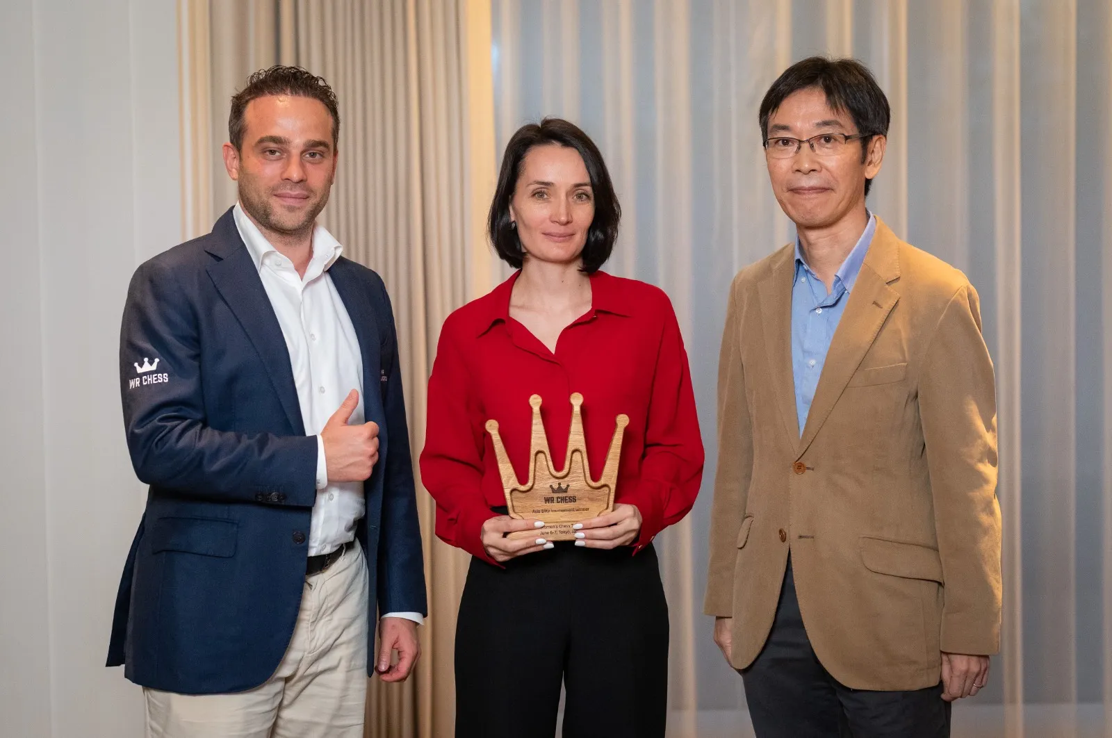Kateryna Lagno receives the Tokyo Blitz trophy, flanked by WR Chess founder Wadim Rosenstein and Japan Chess Federation President Hiroshi Manabe.